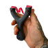 Black slingshot with red band held in a hand against a white background